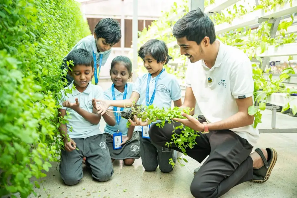 Young students exploring plants with a teacher in the campus greenhouse